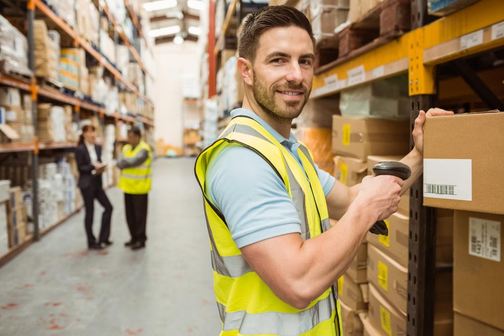 Warehouse worker scanning boxes with barcode scanner.